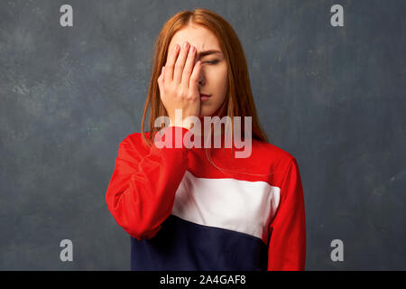 Giovane donna mette mano alla faccia di vergogna. facepalm Foto Stock