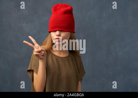 Adolescente tirando verso il basso Red Hat, mantenendo gli occhi chiusi Foto Stock