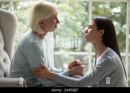 Sconvolto empatico giovane donna che mostra il supporto a madre. Foto Stock