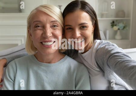 Felice cresciuti figlia tenendo selfie con madre sorridente. Foto Stock