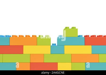 3D rendering di coloratissimi muro fatto di molti mattoni giocattolo con un pezzo rimanendo inutilizzata su sfondo bianco. Foto Stock