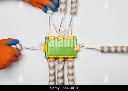 Il condotto con la cassetta di derivazione elettrica sul muro a secco. Collegamento cablaggio domestico al pannello di distribuzione sul retro della parete di un muro a secco. Insta Foto Stock