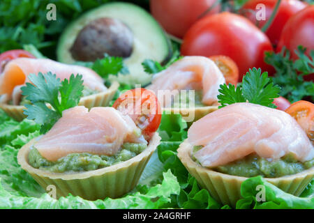 Crostini con guacomole e salmone su uno sfondo vegetale Foto Stock