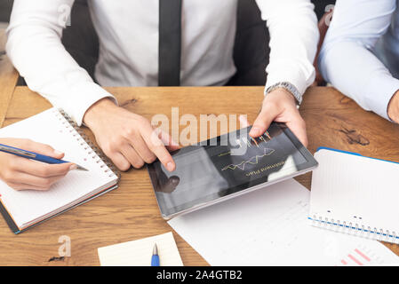 La gente di affari team analizzando i dati finanziari sulla tavoletta digitale. Riunione aziendale presso l'ufficio close up Foto Stock