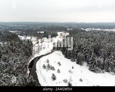 Bella vista aerea di neve coperta di foreste di pini e di un avvolgimento su strada tra alberi. Rime ghiaccio e gelo trasformata per forte gradiente di alberi di copertura. Scenic paesaggio invernale nea Foto Stock