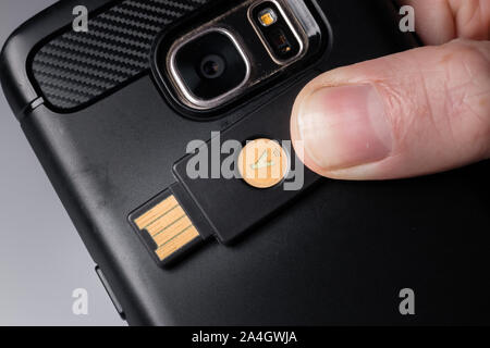 Un Yubikey 5 chiave di sicurezza utilizzando la tecnologia NFC per connettersi a uno smartphone Foto Stock