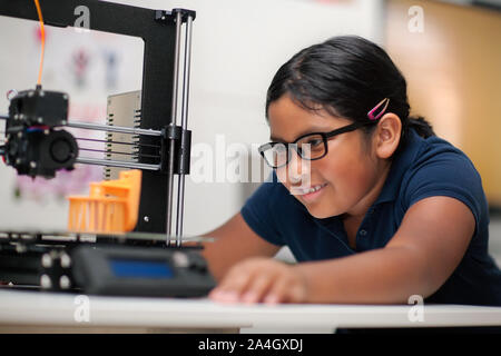 Un felice ragazza con gli occhiali e la visione di una stampante 3d finire il modello 3d ha creato. Foto Stock