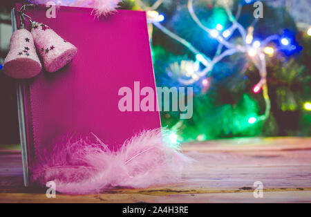 Un grande augurio natalizio prenota con albero di Natale giocattoli e decorazioni sul tavolo di legno contro l'albero di Natale. Una lettura del blocco note di cuoio - un regalo per Natale o Foto Stock