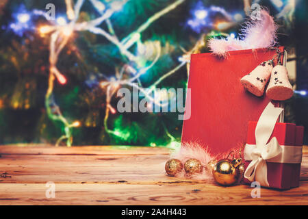 Un grande augurio natalizio prenota con albero di Natale giocattoli e decorazioni sul tavolo di legno contro l'albero di Natale. Una lettura del blocco note di cuoio - un regalo per Natale o Foto Stock