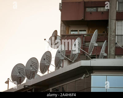 Parabole satellitari e antenne sul display nella parte superiore di un edificio aziendale al tramonto. Questi sono utilizzati per le comunicazioni e la trasmissione delle informazioni. Foto Stock