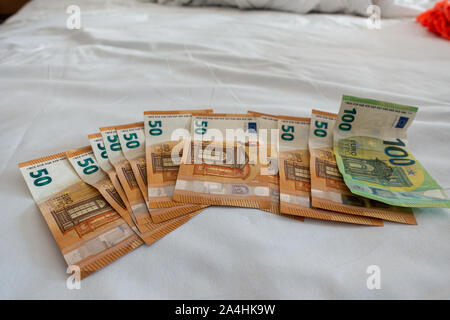 Molte le banconote in euro sono sparsi su un letto con un bianco copripiumino Foto Stock