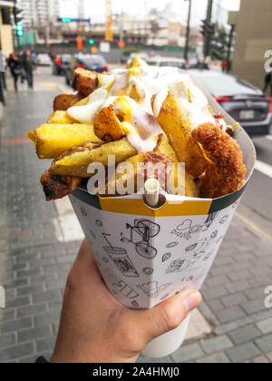 Fast food street a Lima - Perù, patatine fritte e pollo fritto con maionese tra le altre creme in un cono Foto Stock