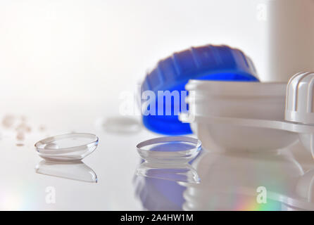 Le lenti a contatto si riflette sul tavolo di vetro con lente caso e gocce d'acqua. Composizione orizzontale. Vista frontale. Foto Stock