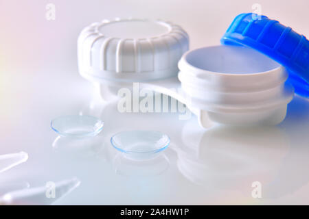 Le lenti a contatto e caso riflessa sul vetro bianco tavolo. Composizione orizzontale. Vista frontale. Foto Stock