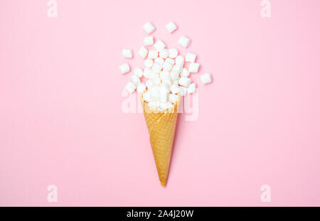 Cono di cialda con il bianco mini marshmallows su uno sfondo rosa vista superiore piatta copia laici spazio Foto Stock