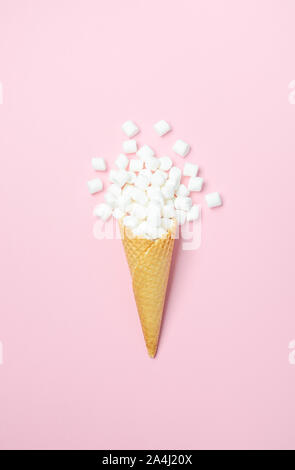 Cono di cialda con il bianco mini marshmallows su uno sfondo rosa vista superiore piatta copia laici spazio Foto Stock