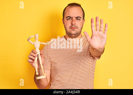 Giovane Azienda figura d'arte permanente dummy isolato su sfondo giallo con mano aperta facendo segno di stop con gravi e fiducioso di espressione, d Foto Stock