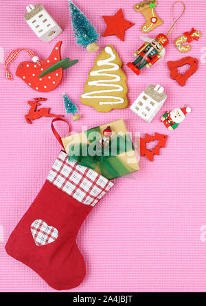 Festa di Natale concetto con i bambini di calze riempite con i cookie e i doni su pop colore sfondo rosa. Foto Stock