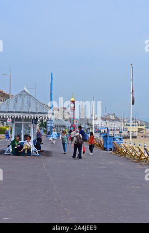 Vista in lontananza Giubileo Torre dell Orologio sulla spianata con tradizionale pubblico vittoriano shelter in primo piano. Persone passato a piedi sul lungomare. Foto Stock