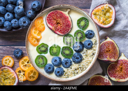 Un organico fresco frullato di yogurt ciotola visto dal di sopra con una variazione di frutta fresca - mirtilli, mini kiwi, fichi, frutto della passione e kumquat. Alcuni Foto Stock