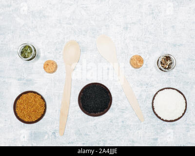 Spezie ed erbe contribuiscono a mantenere in buona salute e a migliorare l'appetito, vista dall'alto sul cemento bianco sullo sfondo. Nero, cumino, di carvi, noce di cocco, fiocchi, erbe aromatiche Foto Stock