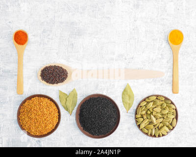 Diverse le spezie e le erbe impostato su sfondo concreto nella piastra di argilla e cucchiaio. Moderno speziale, naturopatia e ayurveda concetto. Foto Stock