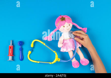 Kid mani con stetoscopio giocattolo, poco bambola giocattolo e strumenti  medicina su fondo azzurro. Bambini medico, il concetto di medicina Foto  stock - Alamy