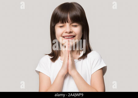 Carino bambina tenere le mani in preghiera alla preghiera a Dio Foto Stock