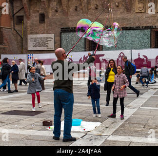 Bologna / Italia - 12 Ottobre 2019: Street performer rende grandi bolle di sapone in Piazza del Nettuno di Bologna, Italia. I bambini raccogliere felice intorno a lui. Foto Stock