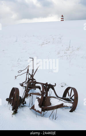 Rusty macchina agricola. Il faro in background. Alnes, GodÂØya. Foto Stock