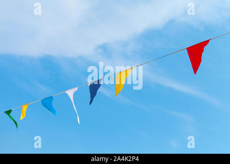 Triangolo colorati Bandiere appeso sulla corda blu su sfondo con cielo nuvoloso Foto Stock