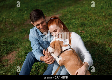 Sorridente coppia romantica insegnamento cane a dare la sua zampata, vicino la foto ritagliata, gara calda sensazione emozione Foto Stock