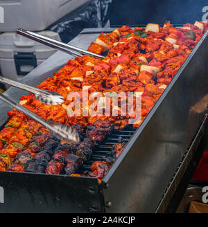 Grigliare gli spiedini di pollo in un giamaicano stand alimentari in un mercato notturno Foto Stock