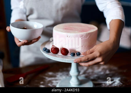 Lo chef tenendo un recipiente con frutti di bosco, rendendo torta per matrimonio. close up foto ritagliata Foto Stock