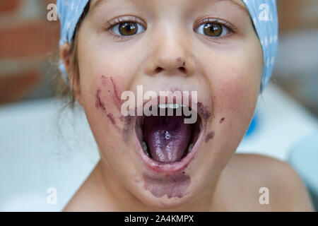 Ritratto di una bambina con la bocca aperta dopo aver mangiato bacche di gelso Foto Stock