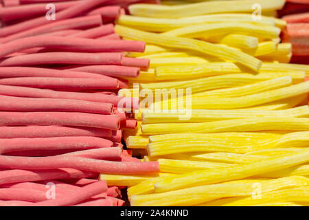 Marshmallow stick rosso giallo rosa, close-up sfondo. Caramella dolce marmellata di arance in un supermercato. Un gran mucchio di frutta dolci di bacche con jell Foto Stock