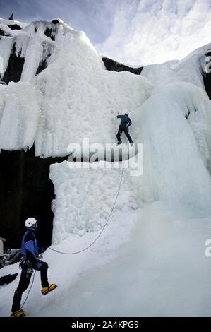 Gli uomini salendo un gelido rock in Norvegia. Foto Stock