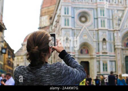 Turista femminile prendendo phot tramite smartphone del Duomo di Firenze in Italia. Foto Stock