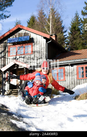 Madre e figlio e figlia giocare nella neve Foto Stock