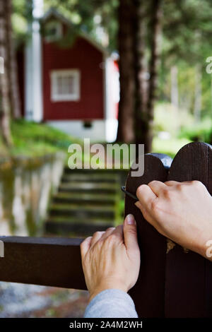 Donna apertura cancello cottage - ingresso - accesso - valutazione - visitatore Foto Stock
