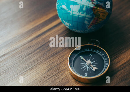 Una singola bussola d'oro accanto a un piccolo globo blu Foto Stock
