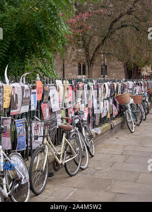 Cambridge, Regno Unito - 9 Ottobre 2019: Biciclette parcheggiate contro la recinzione con un sacco di poster. Foto Stock