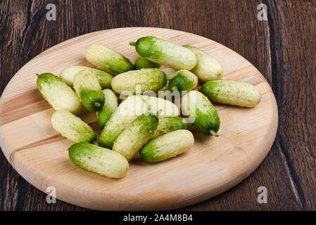 Fresche e mature cetrioli piccoli su un tagliere di legno. Stile rustico. Foto Stock