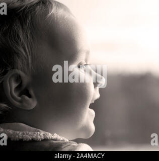 Poco felice ragazza guardando fuori della finestra - in attesa di qualcuno. Foto Stock