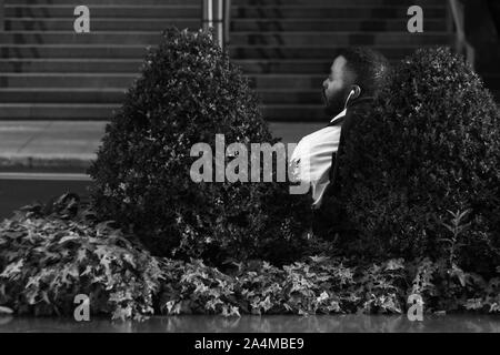 Londra / Regno Unito - 25 agosto 2017 - Uomo seduto in attesa di Bus in Canary Wharf Foto Stock