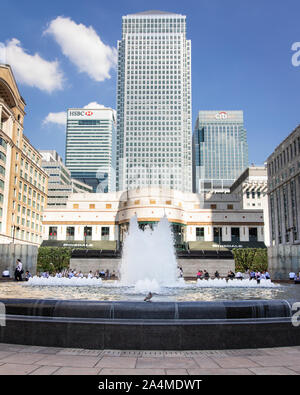 Londra / Regno Unito - 20 Aprile 2018: piccione si fermò sulla fontana di fronte a Canary Wharf grattacieli Foto Stock