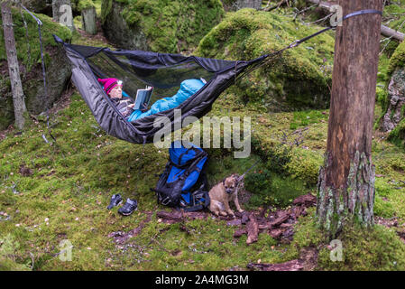 Donna libro lettura in amaca in foresta Foto Stock