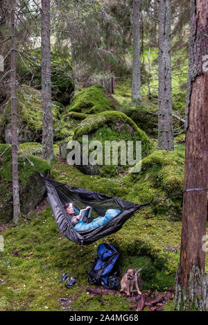 Donna libro lettura in amaca in foresta Foto Stock