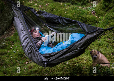 Donna libro lettura in amaca in foresta Foto Stock