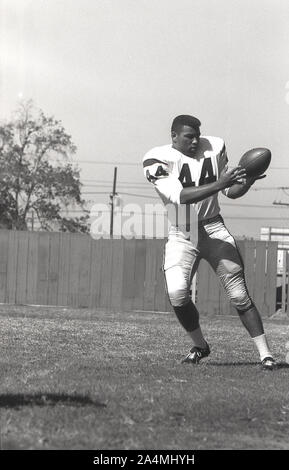 1964, storico, football universitario di Roses, estate e un giovane uomo nero in America che si allena con il pallone alla University of Southern California, Los Angeles, USA. Foto Stock